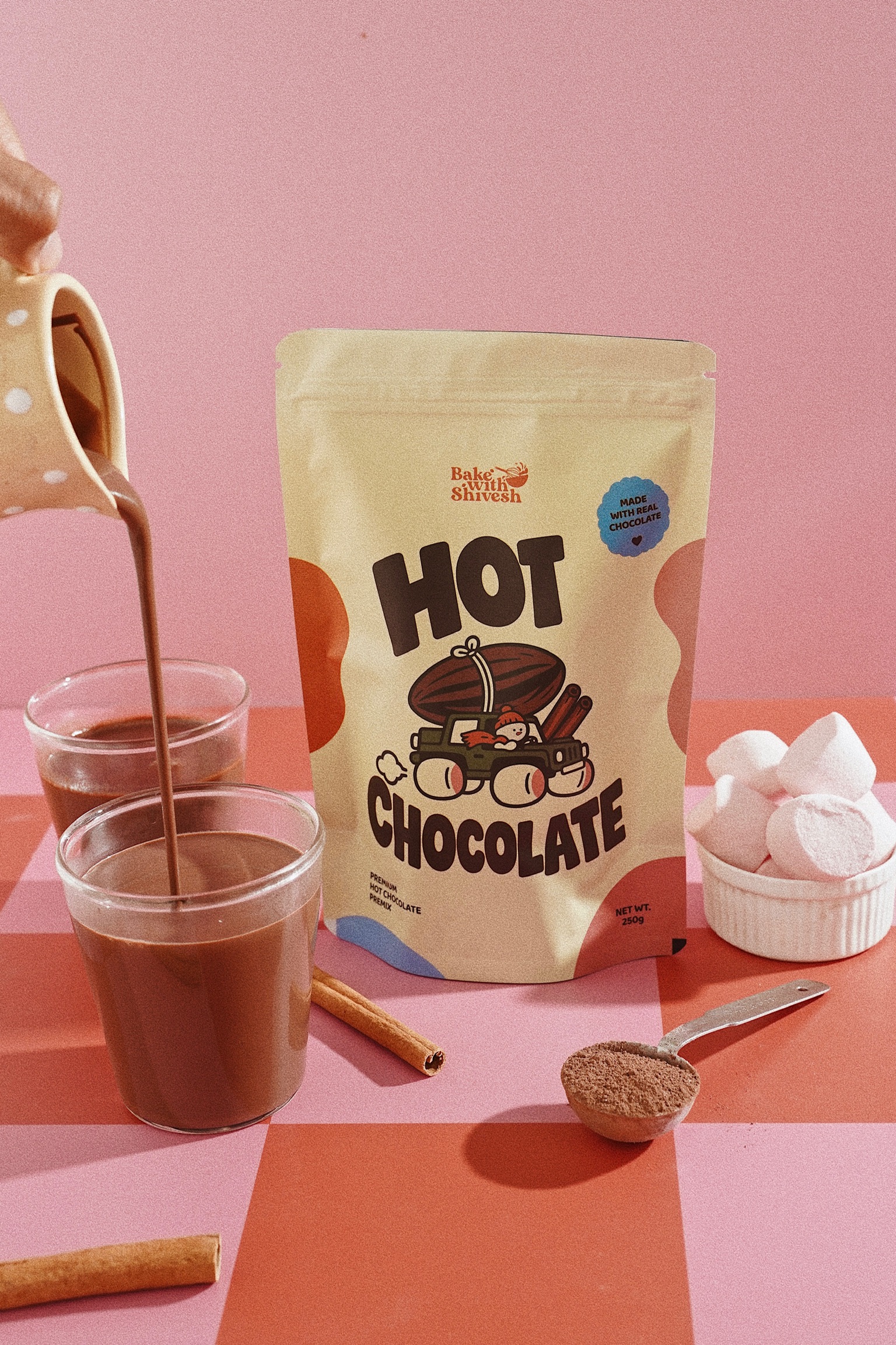 Hot chocolate being poured beside the Bake With Shivesh Hot Chocolate Premix pouch